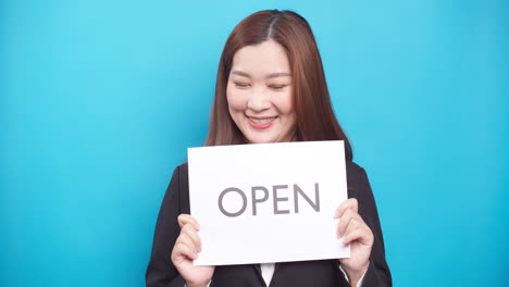 Asian-business-woman-holding-paper-the-text-OPEN-with-a-happy-smile-and-excited-face-in-sale-advertising-and-copy-space