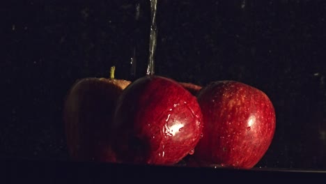 Water-droplets-falling-onto-red-apple