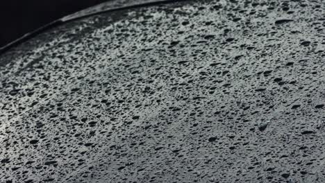 Light-rain-water-droplets-falling-on-exterior-car-window-on-a-dark-gloomy-day