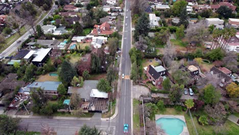 Dolly-in-aerial-view-of-a-main-street-with-little-traffic-and-exclusive-houses-on-the-sides