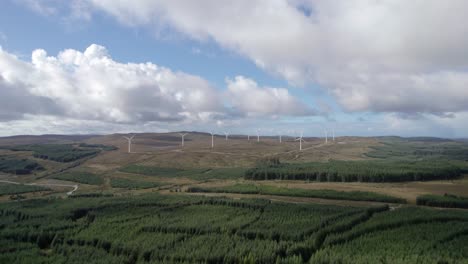 Aerial-drone-footage-of-multiple-turning-wind-turbines-in-a-Scottish-windfarm-surrounded-by-forestry-plantations-of-commercial-conifers-on-the-Kintyre-Peninsula,-Argyll,-Scotland