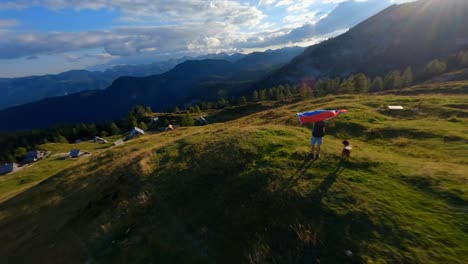 Fpv-footage-was-filmed-in-the-Slovenian-mountain-village-in-the-alps-with-a-drone-flying-fast-over-mountains-filmed-with-a-GoPro-with-incredible-surrounding-landscapes-with-a-hiker-holding-a-flag