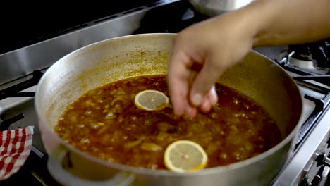 Fresh-Yellow-Sliced-Lemon-Being-Placed-In-Simmering-Curry-Sauce-And-Being-Stirred