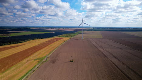 Aerial-view-of-rotating-wind-turbine-and-installed-photovoltaic-area-in-colorful-farm-fields