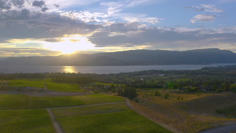 Aerial-view-of-wineries-and-the-Okanagan-Lake-as-the-sun-sets-behind-the-mountains-on-a-warm-summer-day