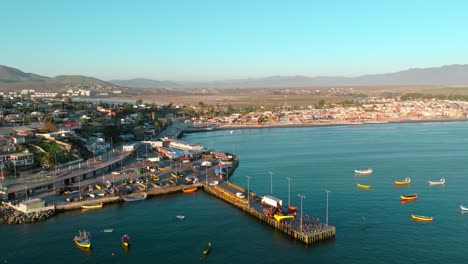 Panoramic-aerial-view-of-the-Tongoy-dock-with-the-boats-in-the-parking-lot-and-anchored-on-the-shore-with-the-arid-mountains-of-northern-Chile-in-the-background