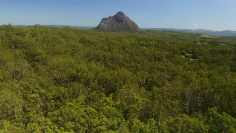 4K-Aerial-Drone-Reveal-Of-Glasshouse-Mountain-Peak-Above-Green-Tree-Forest,-Australia