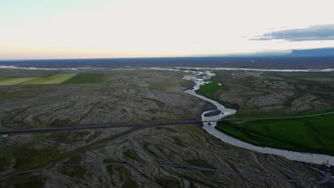 Forward-drone-shot-of-river-and-road-during-midnight-sun-iceland-ring-road