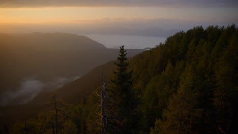 Down-to-up-movement-with-a-gimbal-of-footage-in-the-Slovenian-mountains-up-in-the-alps-at-sunrise-in-beautiful-colors-with-a-camera-going-slowly-forward-overlooking-a-valley-under-the-fog