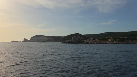 Corsica-island-cliffs-near-Bonifacio-and-Capo-Pertusato-lighthouse-seen-from-Mediterranean-sea-in-France,-slow-motion
