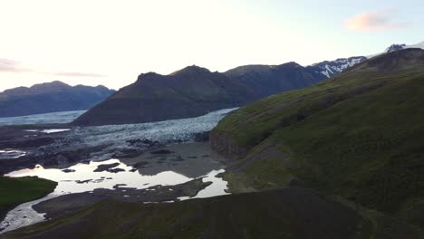 Tiro-Del-Glaciar-Al-Atardecer-En-La-Carretera-De-Circunvalación-De-Islandia,-Dron-Que-Avanza-Reflejo-De-La-Montaña-En-El-Lago-Glacial