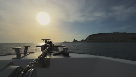 Perspektive-Vom-Segelbootbug-Mit-Strahlender-Sonne-Vor-Und-Felsen-Der-Insel-Korsika-Und-Leuchtturm-Capo-Pertusato-Im-Hintergrund,-Frankreich-1