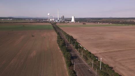 Train-tracks-in-the-middle-of-the-fields-leading-to-a-coal-fired-power-station-in-the-distance