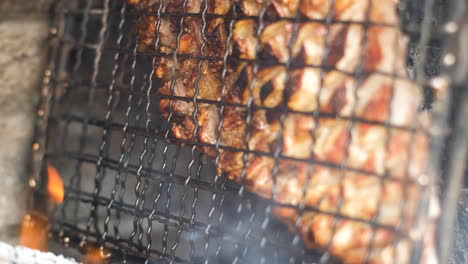 Juicy-lamb-rib-in-grid-dripping-fat---barbecue-on-side-of-wood-fire
