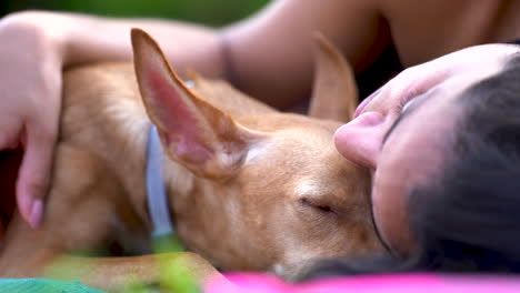 Hound-dog-puppy-resting-with-young-woman-laid-in-the-ground,-taking-a-nap-with-best-friend-close-up