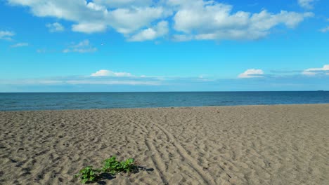 POV-reveals-a-small-sandy,-empty-beach-approaching-the-shoreline-with-horizon