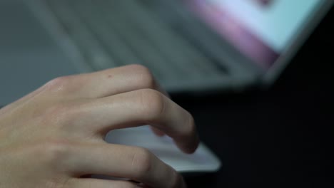 Close-up-of-hand-scrolling,-clicking-a-white-computer-mouse-on-dark-background