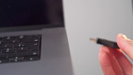 Eine-Nahaufnahme-Einer-Hand,-Die-Ein-USB-Gerät-Im-Alten-Stil-An-Einen-Laptop-Computer-Anschließt