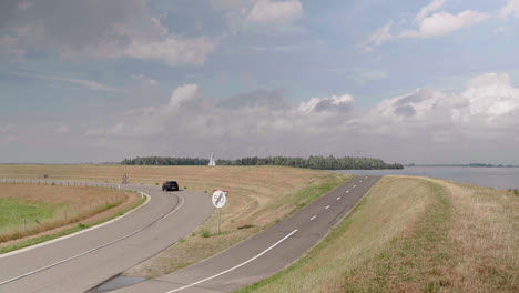 Car-driving-by-in-a-curve-on-a-dutch-polder-dike-road
