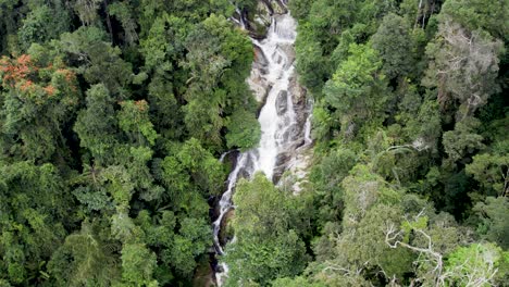 Drone-moves-backwards-and-captures-waterfall-in-the-middle-of-dense-jungle-at-Brinchang,-in-Pahang,-Malaysia