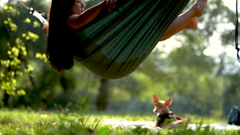 Young-female-mixed-race-model-rock-hammock-in-forest-natural-park-with-her-little-cure-dog