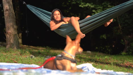 Mixed-race-woman-resting-chilling-on-hammock-in-wilderness-during-a-sunny-day-with-her-faithful-dog