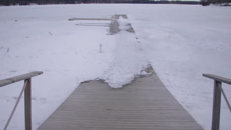 Wooden-boardwalk-path-leading-across-snow-covered-woodland-lake-at-Holiday-Club-Katinkulta-Vuokatti-Finland