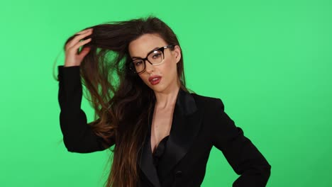 Sexy-long-hair-brunette-young-woman-in-formal-black-business-office-suit-and-glasses-touches-hair-while-looking-at-camera