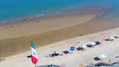 View-of-a-drone-flying-back-showing-a-beach-and-the-Mexican-flag