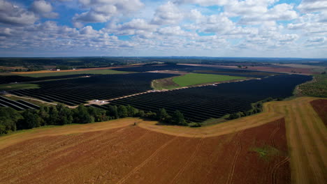 Ascending-drone-shot-of-large-solar-farm-in-countryside-for-eco-friendly-energy-on-earth