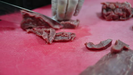 4k:-Chef-cutting-raw-meat-on-a-cutting-board-in-a-professional-kitchen
