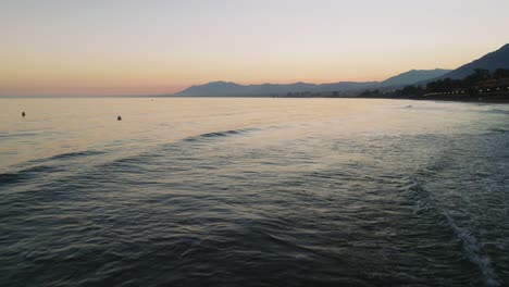 Antenne,-Die-Nach-Sonnenuntergang-An-Einem-Felsigen-Strand-In-Der-Nähe-Von-Marbella,-Spanien,-Rückwärts-Fliegt