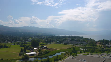 Aerial-view-of-suburban-Kelowna-community-on-a-sunny-day,-near-the-Okanagan-Lake,-with-distant-mountains-visible-in-the-haze