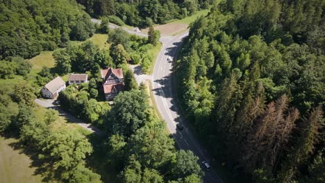 Aerial-Tracking-Shot-Of-Cars-On-A-Remote-Road-Passing-Past-A-Large-Mansion-In-The-German-Countryside