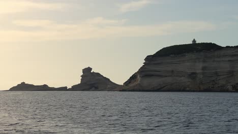 Corsica-island-cliffs-and-Capo-Pertusato-lighthouse-seen-from-Mediterranean-sea-in-France,-slow-motion