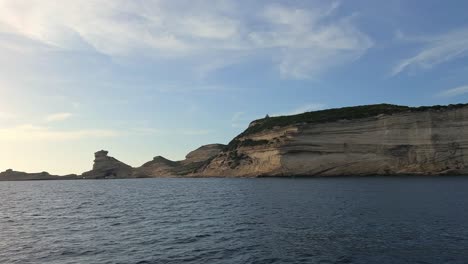 POV-Eines-Segelbootbogens,-Der-In-Richtung-Der-Klippen-Der-Insel-Korsika-Und-Des-Leuchtturms-Von-Capo-Pertusato-In-Frankreich-Navigiert,-50-Fps