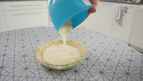 Man-pouring-a-creamy-filling-on-top-of-a-pie-dough