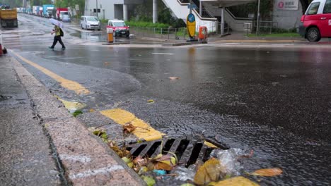 A-city-gutter-drain-collects-a-stream-of-rainwater-as-a-heavy-rainstorm-and-strong-winds-hit-and-disrupts-Hong-Kong-during-a-tropical-Summer-typhoon