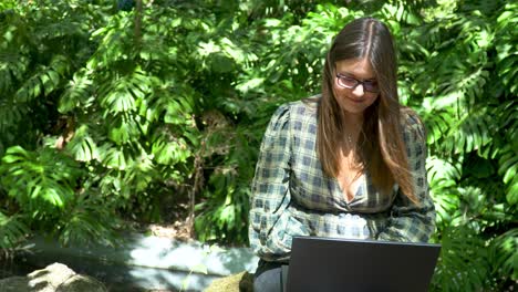 Happy,-smiling-woman-working-online-on-a-notebook-on-a-sunny-day-in-park