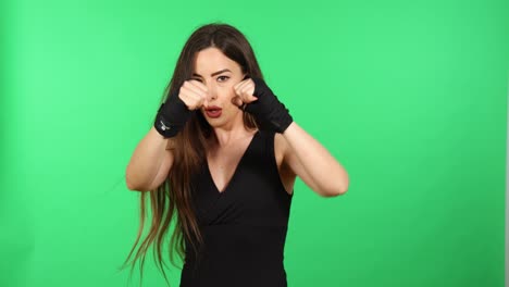 Sportswoman-punching-looking-at-camera-with-boxing-hand-wraps-and-green-screen-in-background