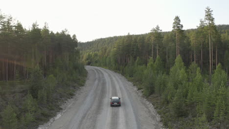 Toma-De-Un-Dron-De-4k-De-Un-Auto-Conduciendo-Solo-En-Un-Camino-Rural-En-Un-Denso-Bosque-En-Suecia