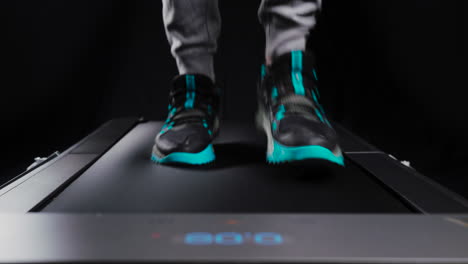 Static-frontal-close-up-shot-of-a-man's-feet-running-on-a-treadmill