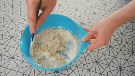 Man-combining-the-ingredients-for-pie-dough-in-a-blue-bowl