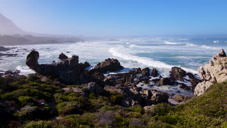 Aerial-tracking-shot-along-rugged-Hermanus-coastline-and-coastal-fynbos