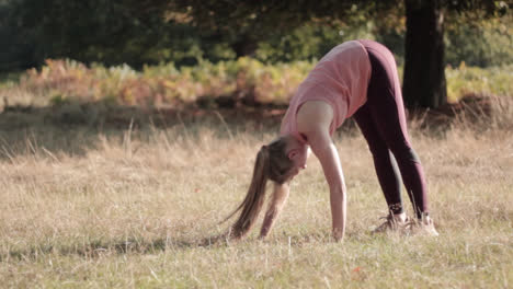 On-a-sunny-day,-a-woman-is-performing-the-downward-dog-yoga-pose-in-the-park-outdoor