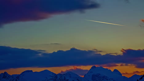 Time-lapse-shot-of-dark-clouds-emerging-at-sky-over-snowy-mountains-in-winter-at-sunset-time