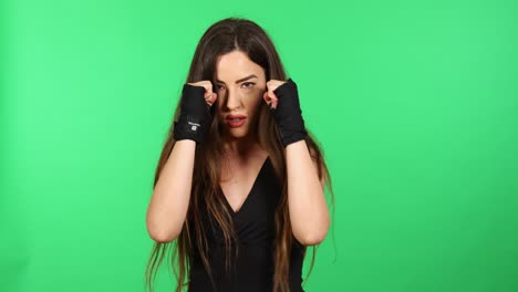 Beautiful-female-boxer-punching-looking-at-camera-with-boxing-hand-wraps-and-green-screen-in-background