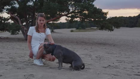 Attractive-woman-petting-her-American-Staffordshire-Terrier-dog-in-sand-dunes