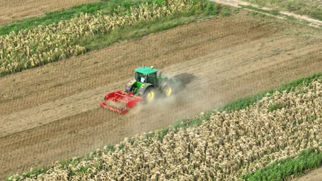 Aerial-tracking-shot-of-green-industrial-tractor-plowing-farm-field