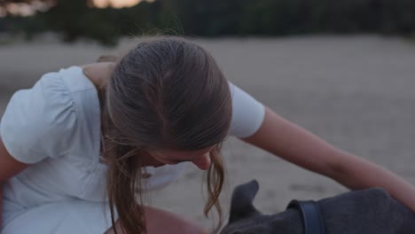 Close-up-of-young-woman-petting-her-American-Staffordshire-Terrier-dog-in-sand-dunes